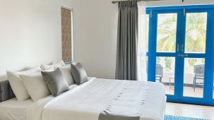 A king bed with blue door to the balcony inside one of the rooms at Azalea by Stone Wood, Orlim