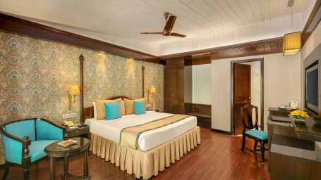 A cozy bedroom with a comfortable bed, warm lighting, and a view of the forest through a large window at Shervani Hilltop Nainital 