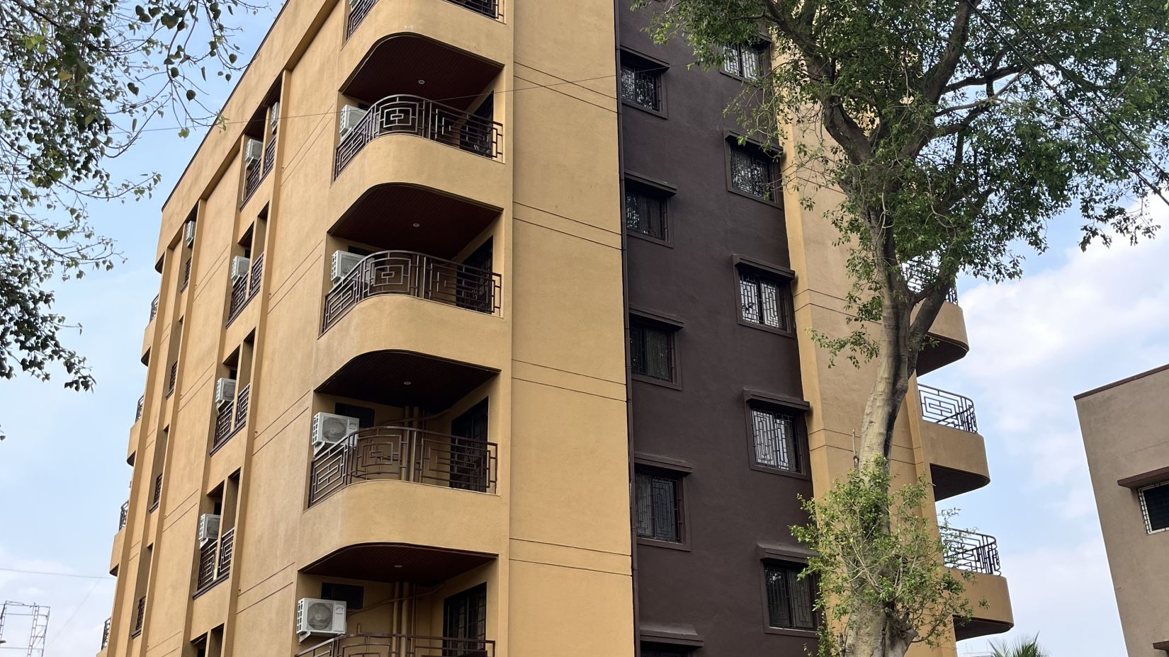 A facade image of a building with a large tree in front - VITS Select Kharadi, Pune