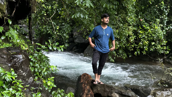 alt-text a person near a stream with a log in front of him - Holistic Stay Eco Resort, Kannur