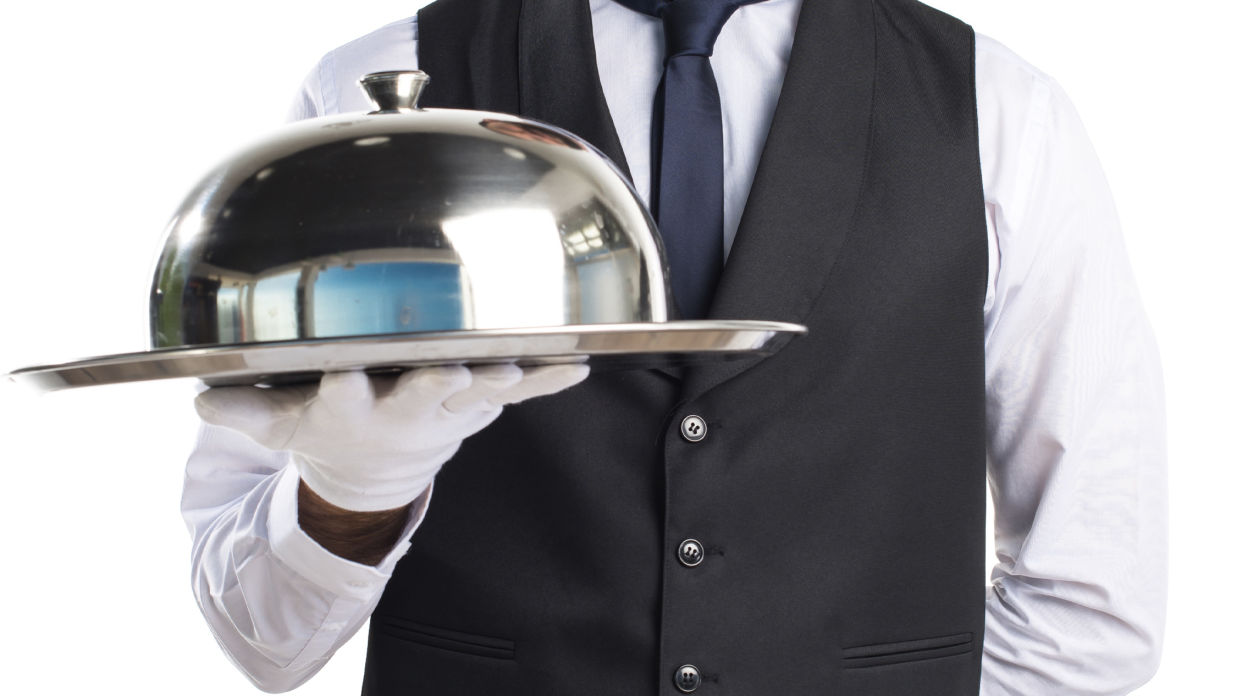 a man holding a cloche for in-room dining