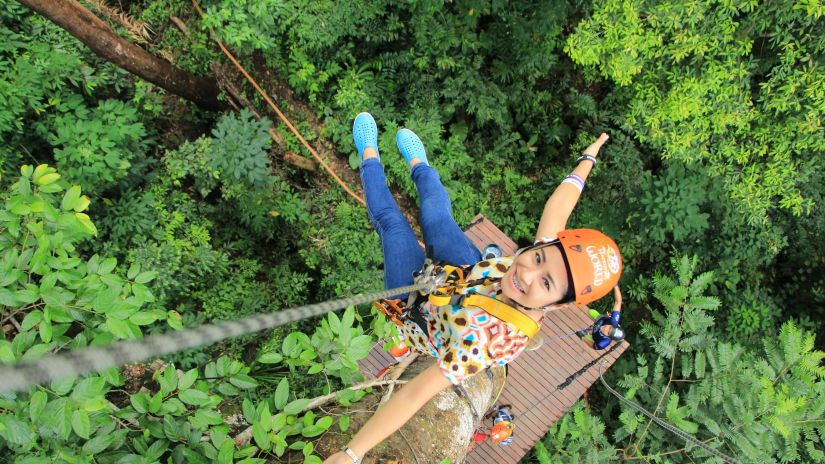 A person enjoying zip lining  in a forest area.