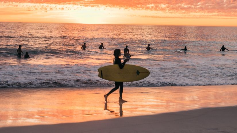 A girl walking with a surf board