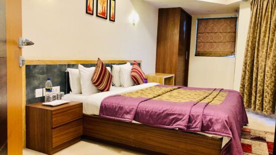 a king bed with side table inside the suite - VITS Kamats Resort, Silvassa