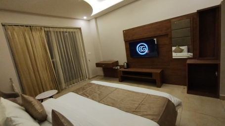 A well-furnished bedroom with a bed and a TV | Stone Wood Hotel, Rishikesh