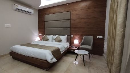 A full view of a bedroom with a bed flanked with bed lamps, a chair, and a table | Stone Wood Hotel, Rishikesh