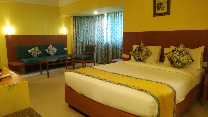 The yellow walls, spacious bed and other furniture inside our hotel room - Lotus Eco Beach Resort Benaulim Goa