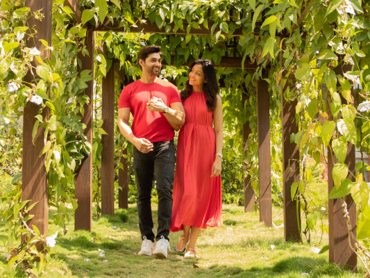 Couple walking through green pathway in garden