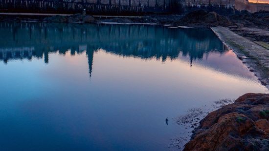 city lake with a building in the background and clouds in different hues during the sun set