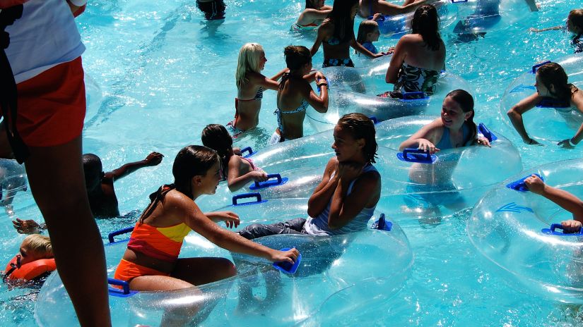 many kids inside a pool with a person standing on the side looking at them