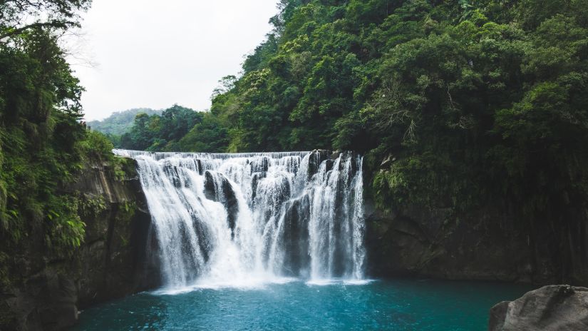 A waterfall with trees on either side and the water cascading into a pool