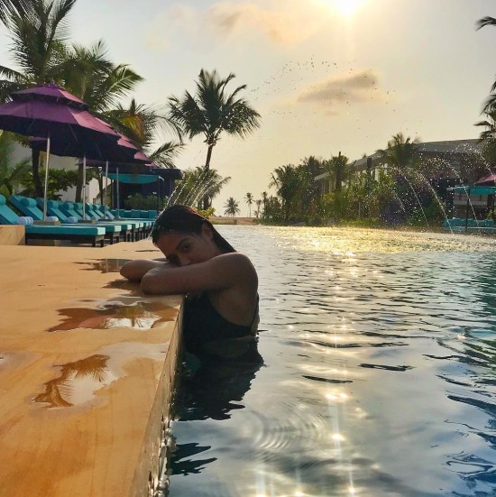 Woman in black bikini standing at a pool's edge