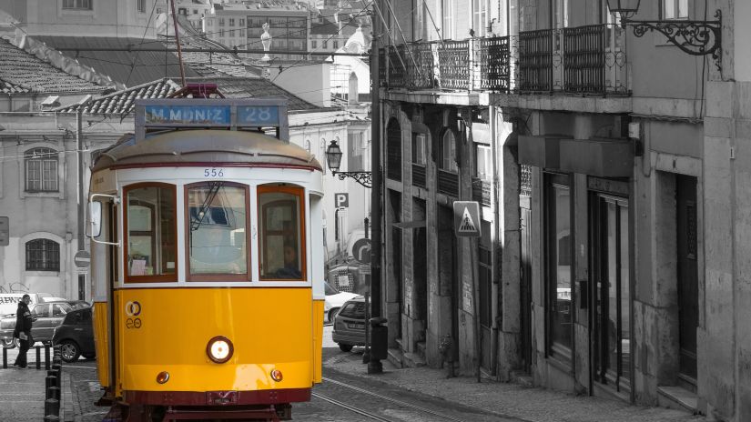 a yellow tram riding in the city of kolkata