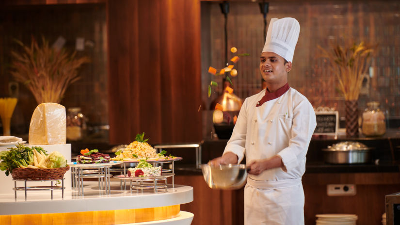 A chef bringing food to the buffet spread