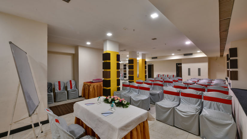 A banquet hall ready for a presentation with a whiteboard and a projector set up - Click Hotel Yuvraj, Surat