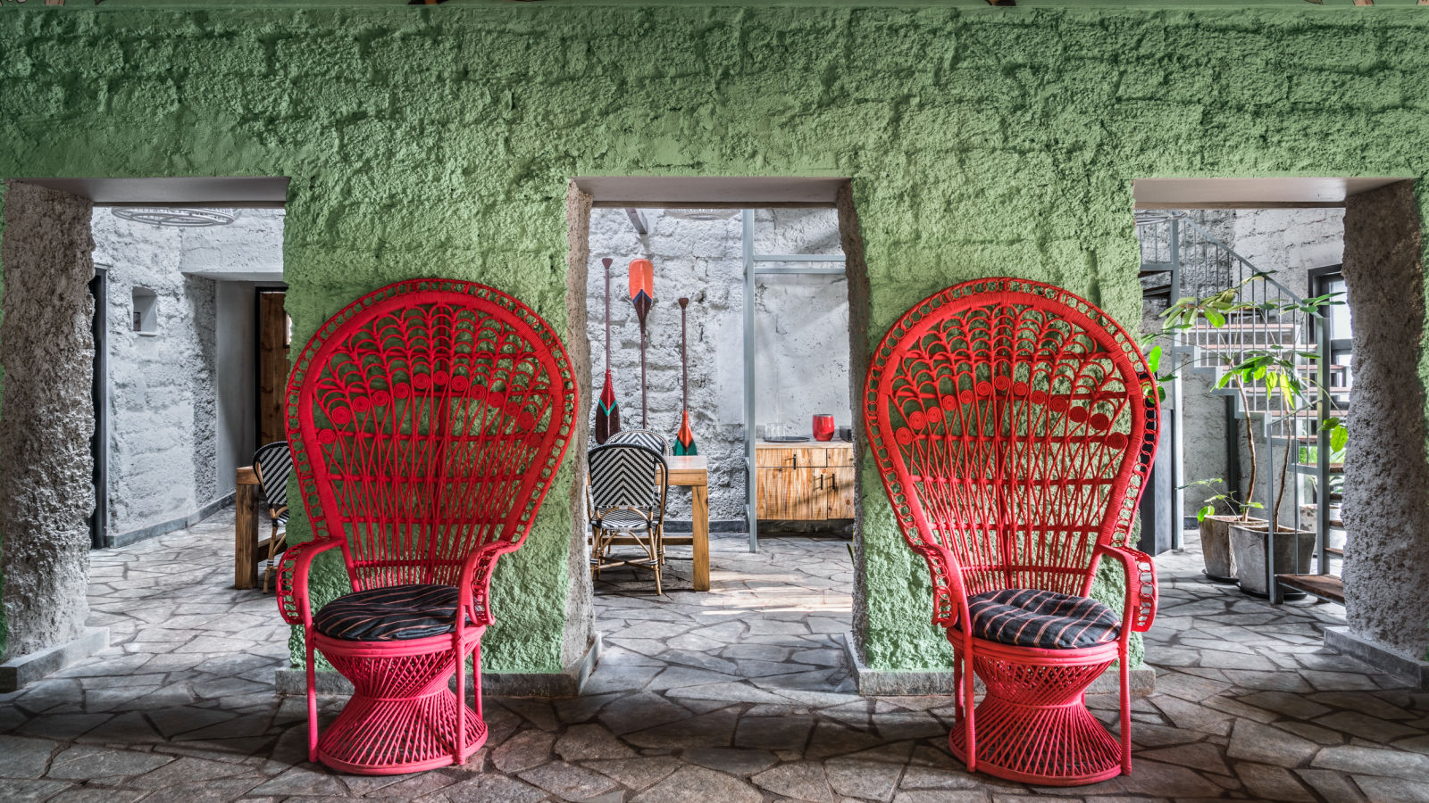 Two red single seaters in front of a green wall with access to a dining section next to it at Village 36