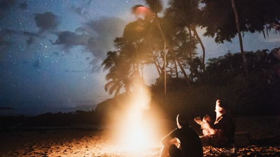 A couple sits close to a bonfire under the starry sky - nightlife in South Goa