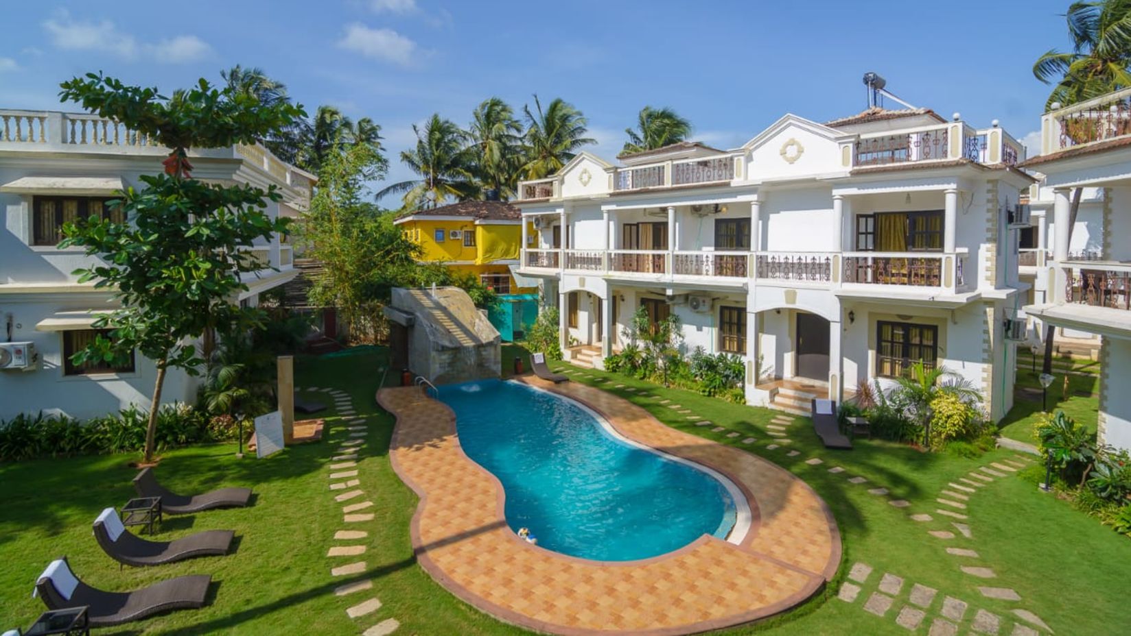 a bird's eye view of the hotel premises shows the pool surrounded by the hotel and palm trees - Richmonde Ananta Elite, Goa