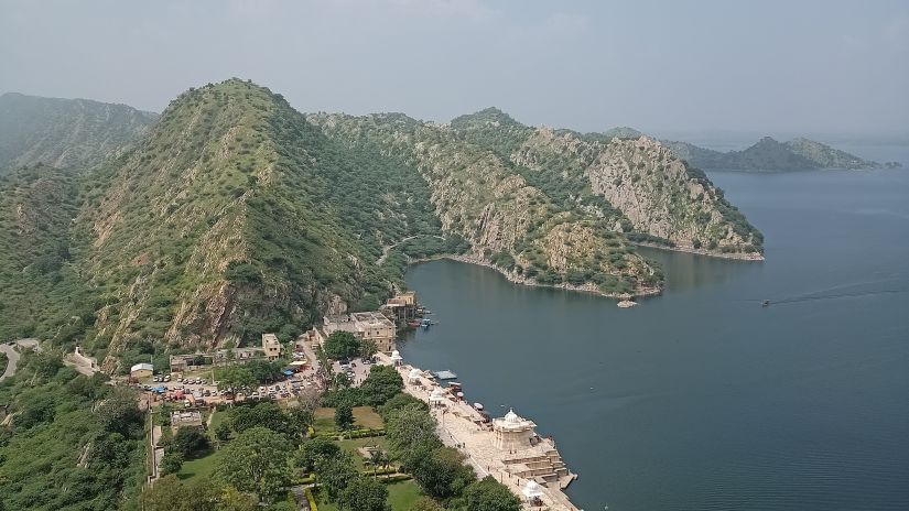 an aerial view of a lake surrounded with hills and greenery