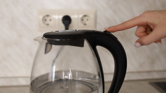 A person turning on an electric kettle @ Lamrin Ucassaim Hotel, Goa