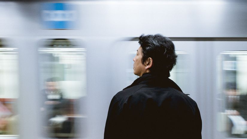 a person looking at a train going past him in a train station