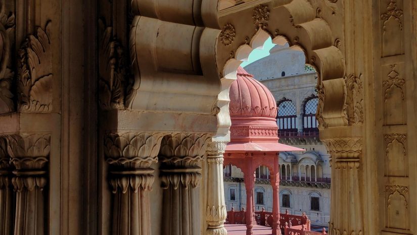 a view from inside a temple at alwar of a small red temple seen from the gaps