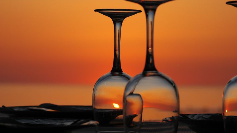 Wine glasses inverted on a table with an orange sky in the background