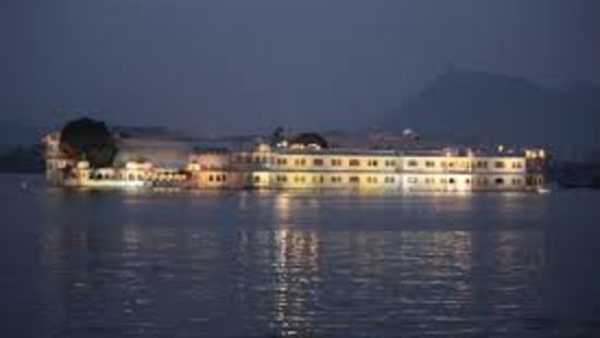 a palace with lights on in lake pichola