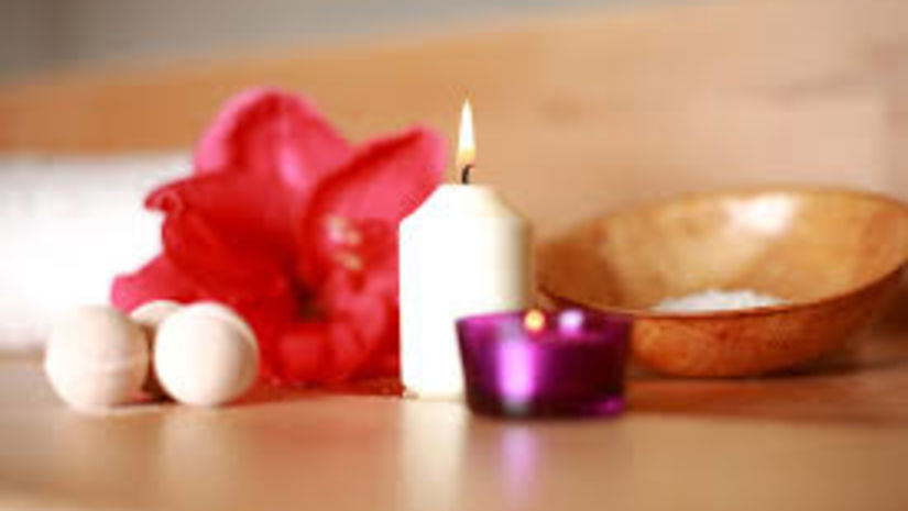 a candle, a flower and other healing objects kept in a spa