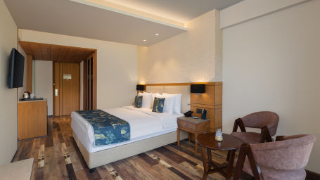 Superior room at Infinitea Centric, Dharamshala with a double bed, seating area, television and storage unit.