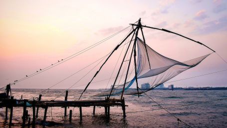 Fishing nets being pulled up with the sun setting in the background at the backwaters of Kochi