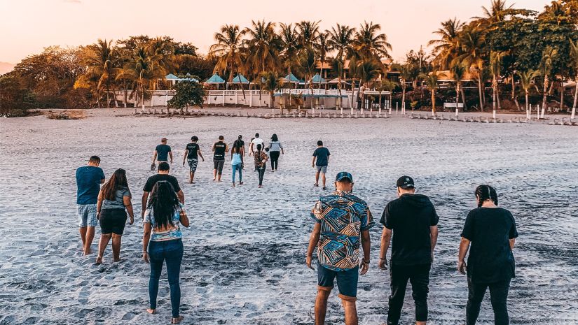 many people walking on beach with trees in the background