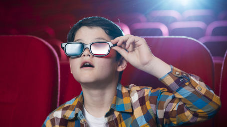 a kid wearing 3-D glasses in a theatre