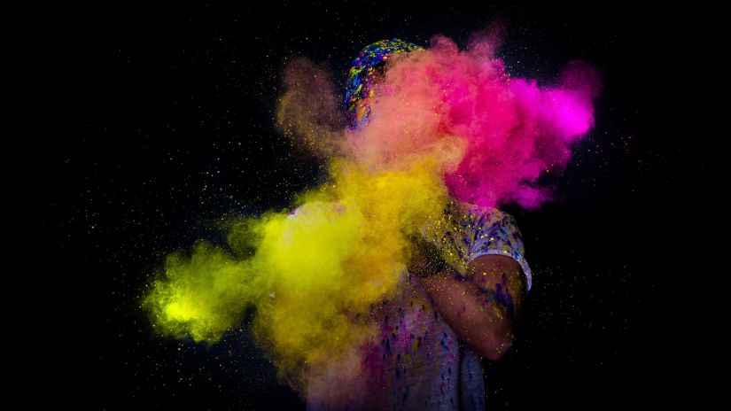 person clapping hands filled with colour powders