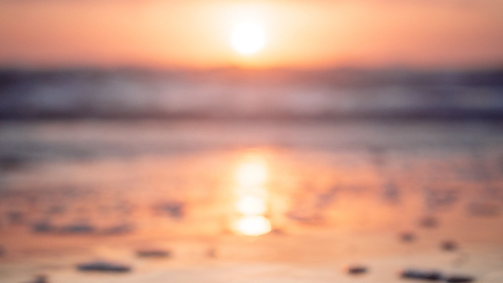 sunset at a beach with rocks engraved in sand