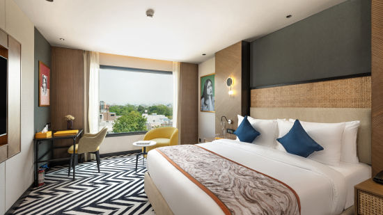 alt-text A room at Parallel Hotels Udaipur with a cozy and comfortable bed, a working desk, tastefully decorated interiors, and a window offering beautiful scenic views, at Parallel Hotel Udaipur