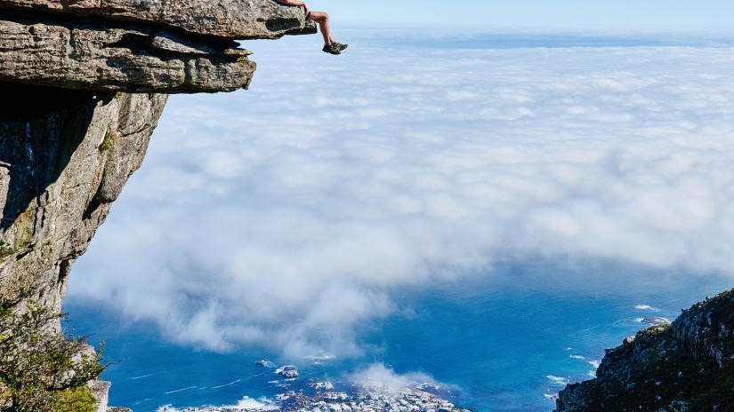 person sitting on mountain cliff