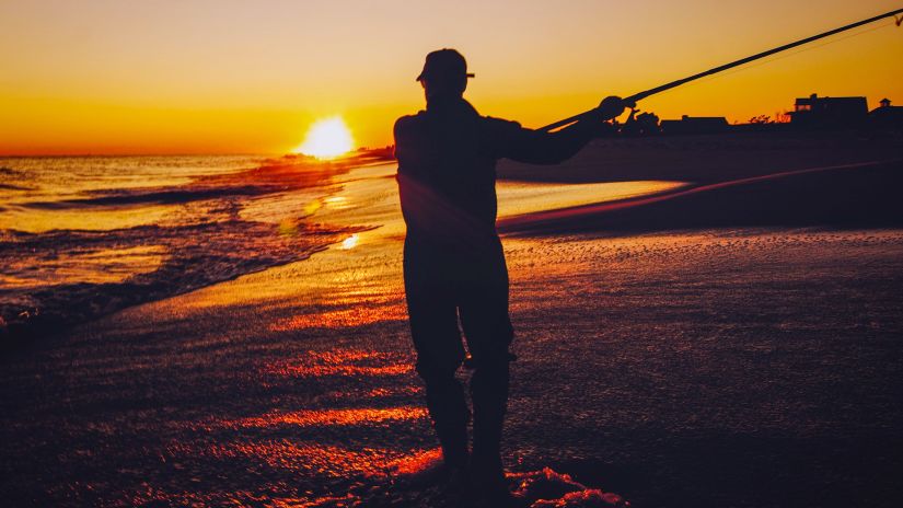 silhouette of a person fishing during sunset