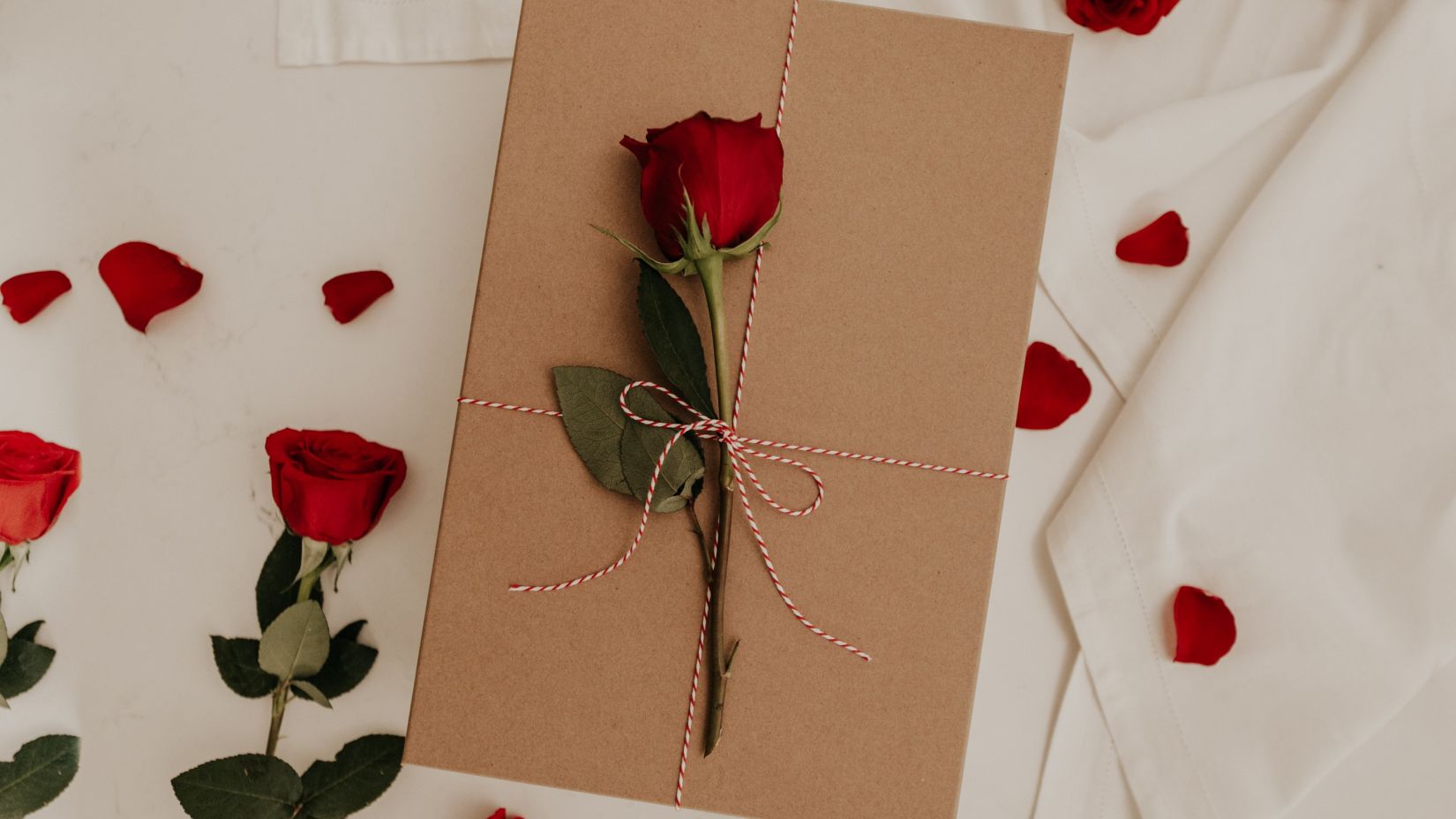 an envelope sealed with a rose on a bed with rose petals and flowers