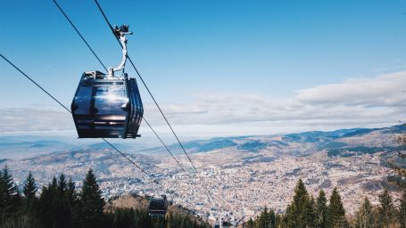 A scenic view of an aerial tramway above pine trees and mountains