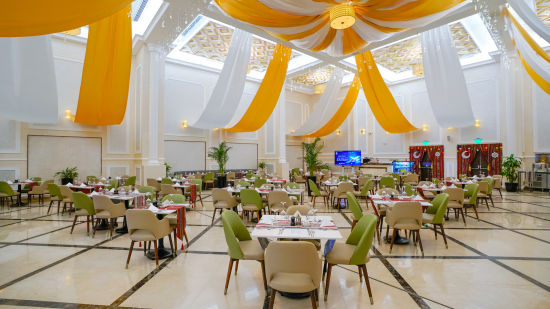 round table seating inside a banquet hall with white and orange cloth above - La Maison Hotel, Doha