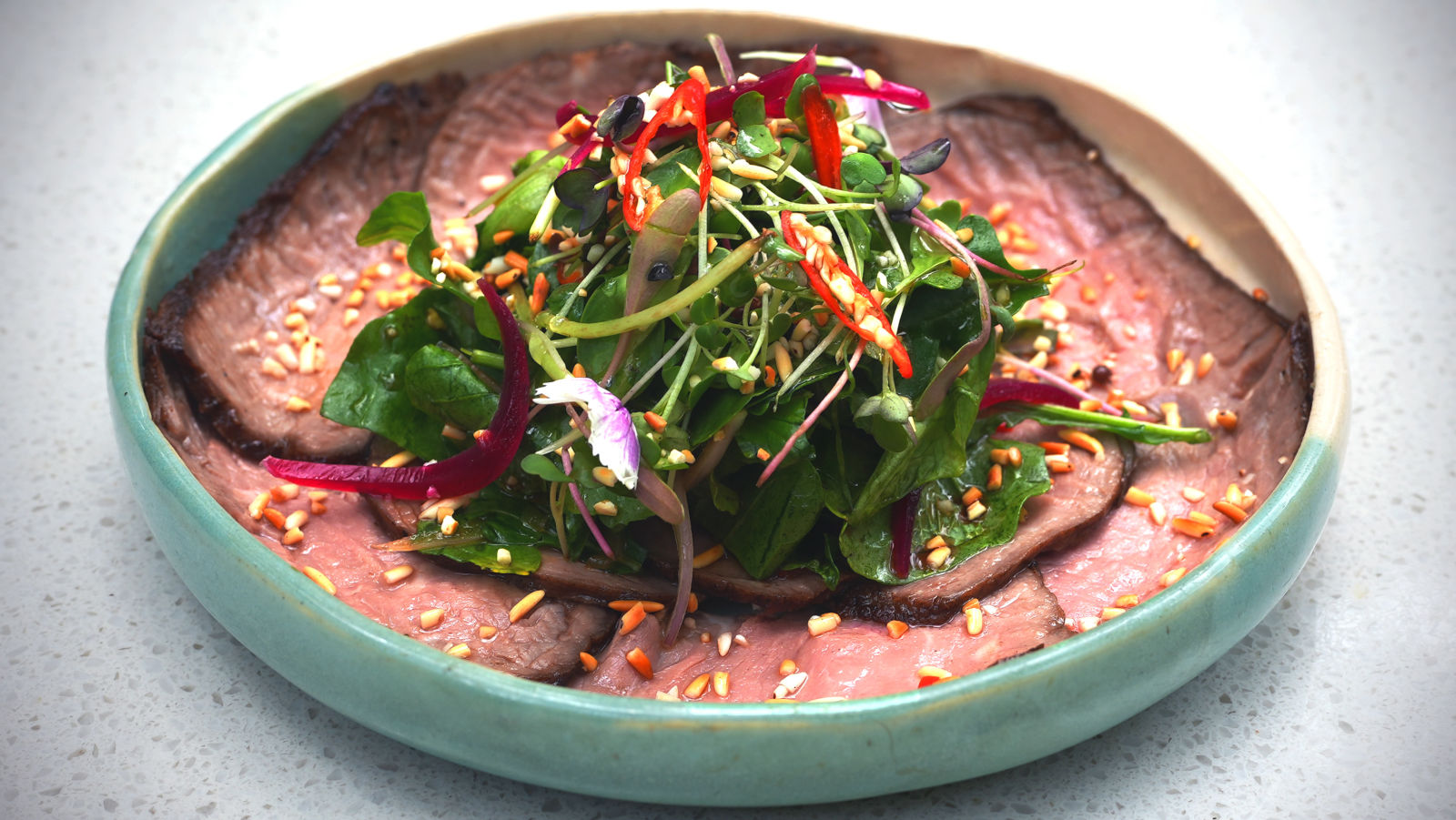 Beef salad in a round ceramic bowl at Village 36