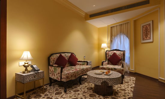 alt-text Front view of the royal seating, two sofas and a small side table in the Suite Cottage Room at The Garden Ananta Elite Rajkot 3