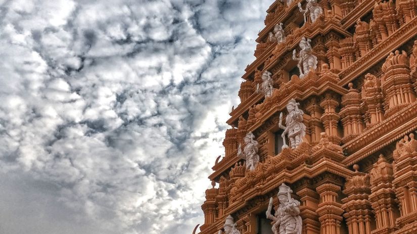 angular facade of a temple with white clouds on blue sky in the background