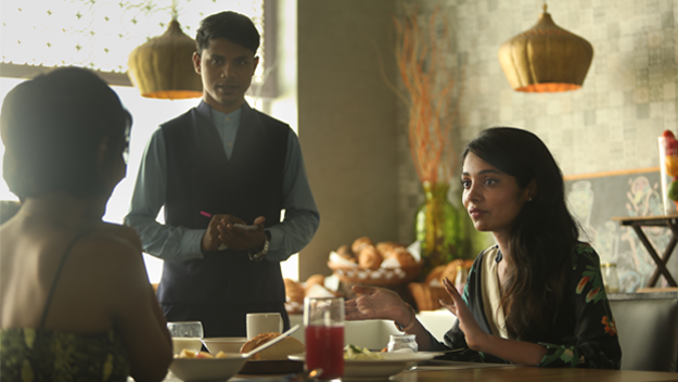 two women dining at our cafe and a waiter standing beside them at The Residency Towers, Rameswaram