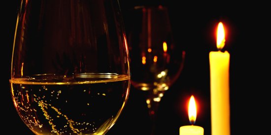 two candles placed beside a glass of wine