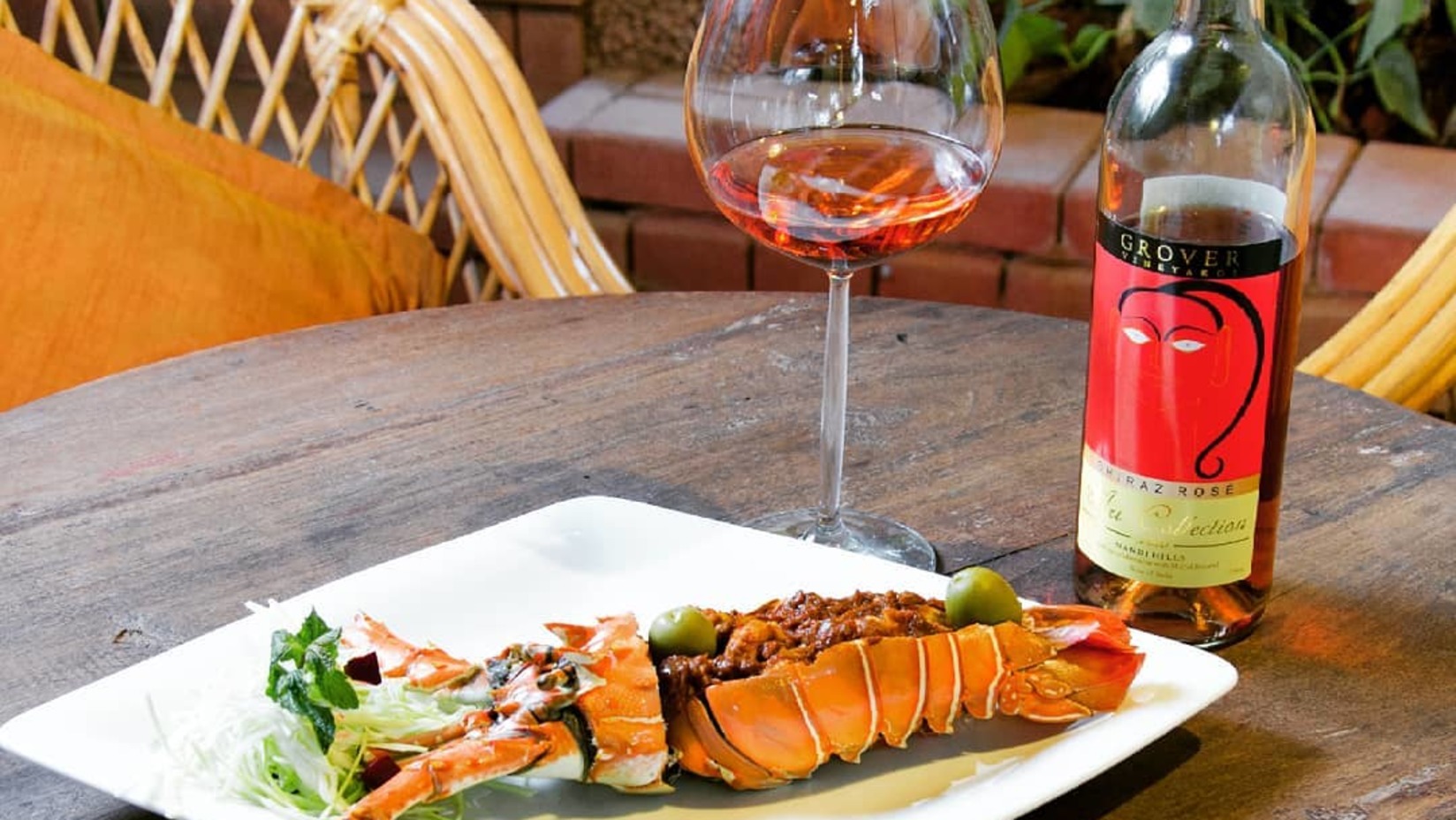 lobster dish next to bottle and glass of rose