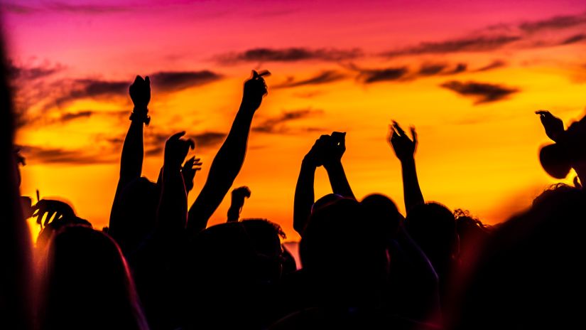 people dancing at a beach party with a sunset sky