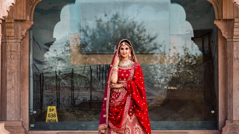 a bride posing for a picture below an arch of a building 