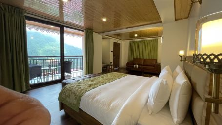 suite room with floor-to-ceiling window offering mountain view and a plush bed